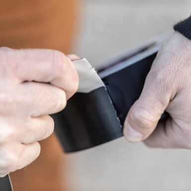 Black roll of T-Rex tape being torn by hand