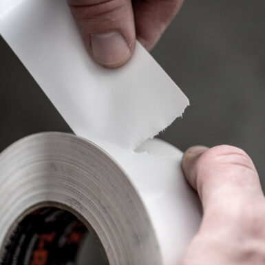 White roll of T-Rex tape being torn by hand