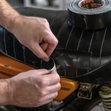 Black strip of T-Rex tape being used to repair a tear on a motorcycle sheet